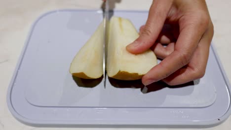 hand slicing a pear on a cutting board