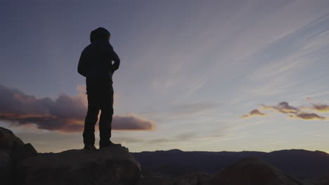 a man stands on the rocks at sunset