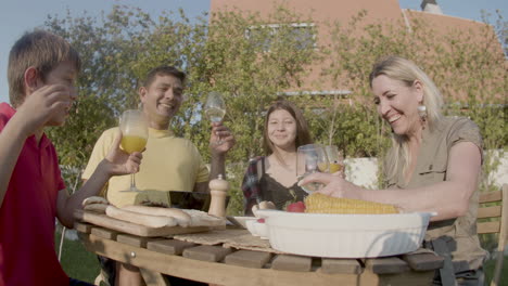 father saying toast and family clinking glasses at garden party