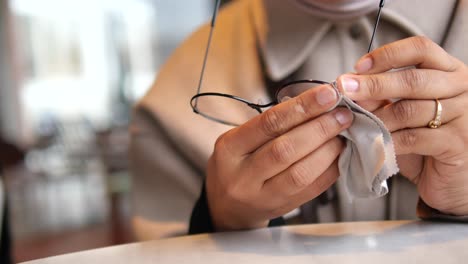 close-up of a person cleaning eyeglasses with a cloth