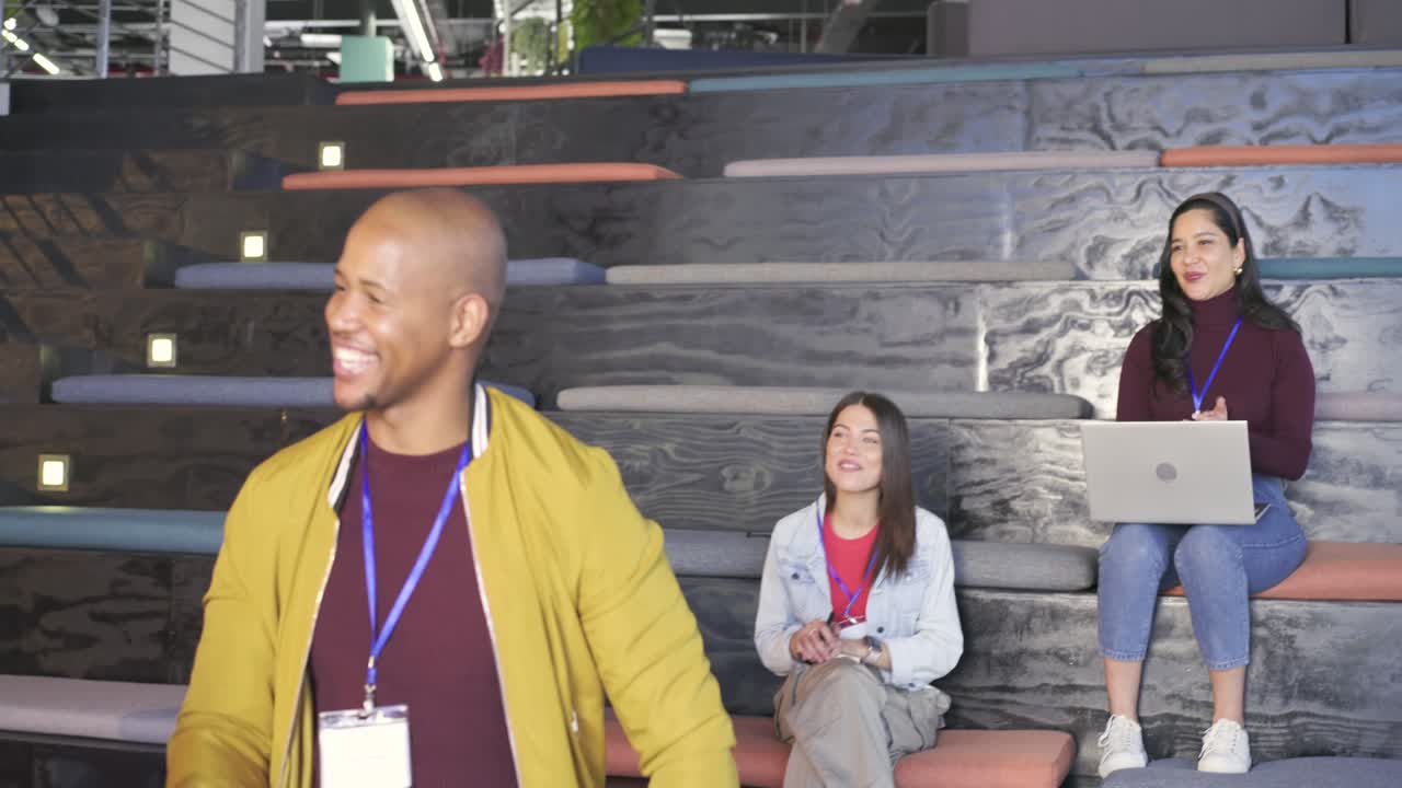 African American man tapping chest with tablet amid office applause, approaching host shaking hand