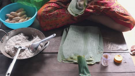 femme emballant des portions de nourriture dans une feuille de banane