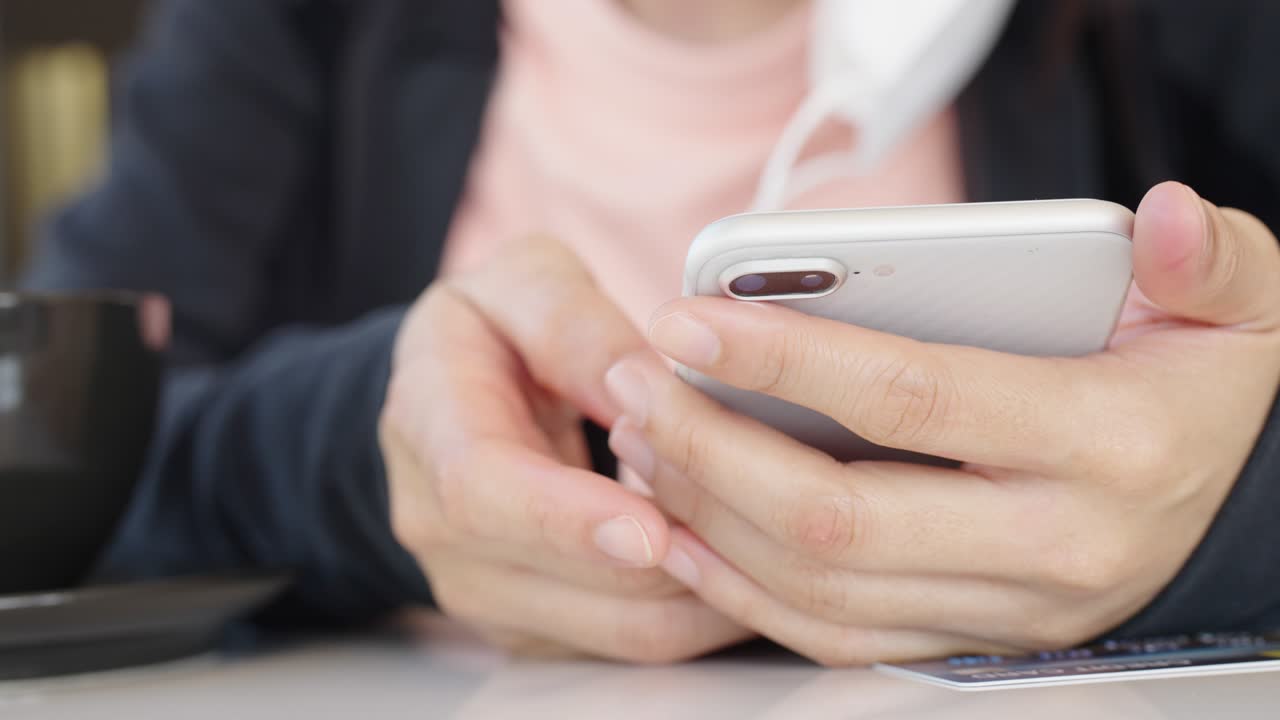 スマートフォンを持ちモバイルアプリを使用する女性の手のクローズアップ。日常生活でのテクノロジー利用、オンラインショッピング、オンライン決済のコンセプト。
