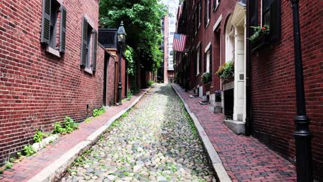 Boston-Beacon-Hill-Acorn-Street-neighborhood-with-brown-brick-federal-style-rowhouses-and-narrow-cobblestone-sidewalk,-gas-lanterns,-US-flag