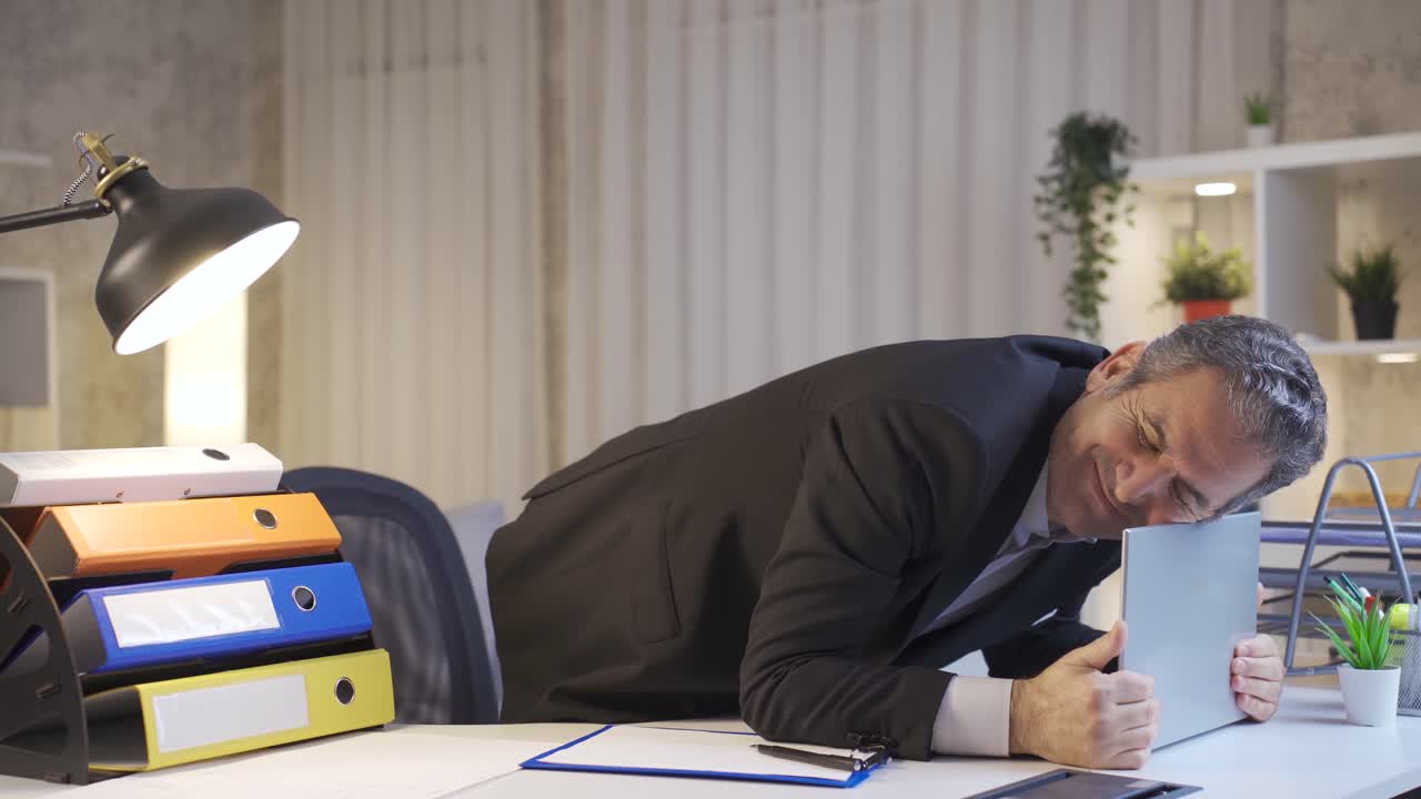 성숙한 사업가가 온라인에서 승리를 축하하고, 집 사무실 책상에서 재미있는 기 ⁇ 의 몸짓을 합니다.