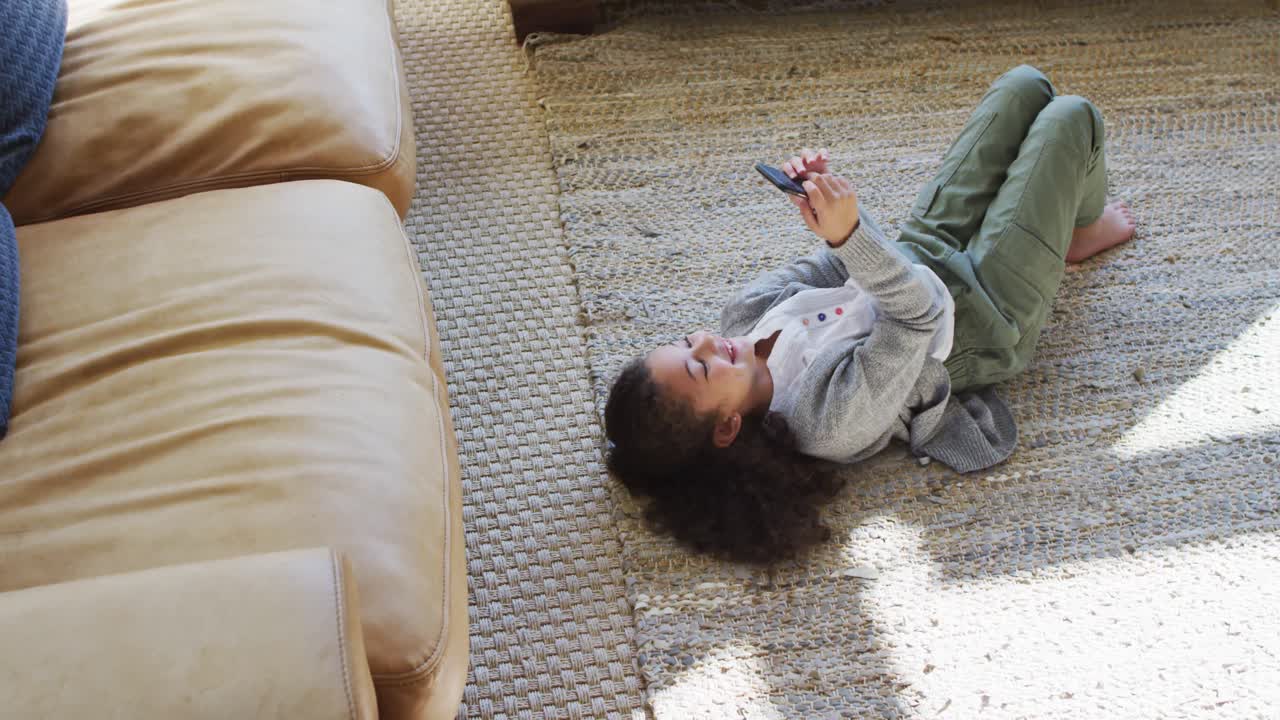 Happy girl laying on the floor,having fun and using smartphone