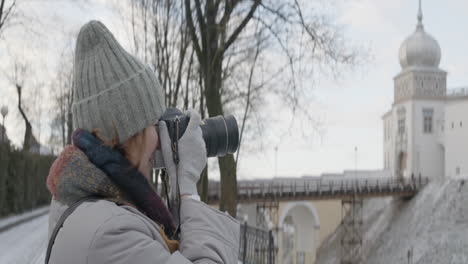 mujer tomando fotos de un castillo en invierno