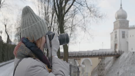 woman taking photos of a castle in winter