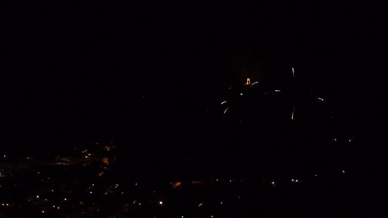 celebración con coloridos y brillantes fuegos artificiales, sobre un pueblo de montaña, por la noche