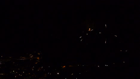 celebración con coloridos y brillantes fuegos artificiales, sobre un pueblo de montaña, por la noche