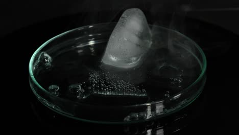 ice cube melting rapidly in a glass dish