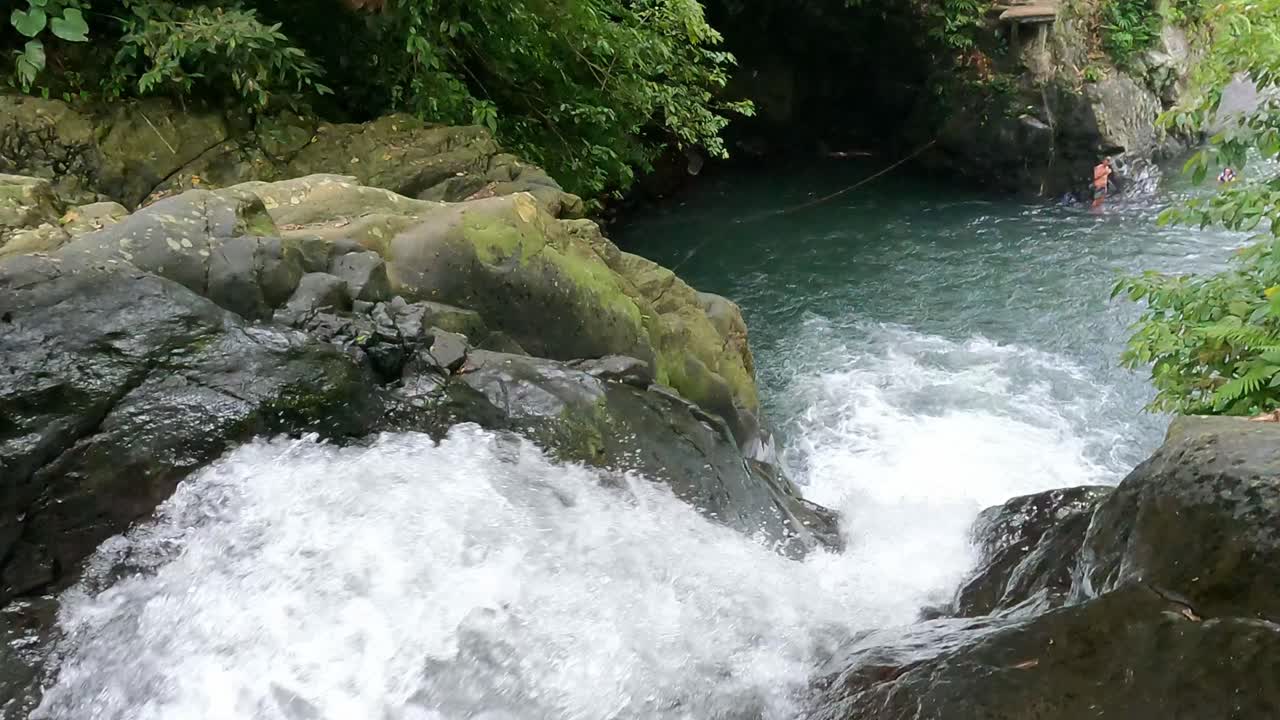 persona adulta en la cascada de kroya deslizándose por un tobogán natural vertical en las cascadas de aling aling, bali