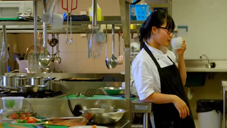 female chef having coffee in kitchen 4k