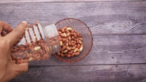 pouring roasted peanuts from a jar into a bowl