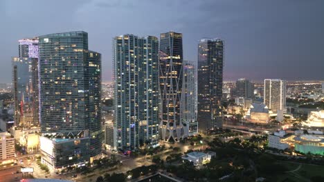 Skyline-Gebäude-In-Der-Innenstadt-Von-Miami-Bei-Sonnenuntergang,-Beleuchtet-Mit-Nachtlicht,-Luftaufnahme