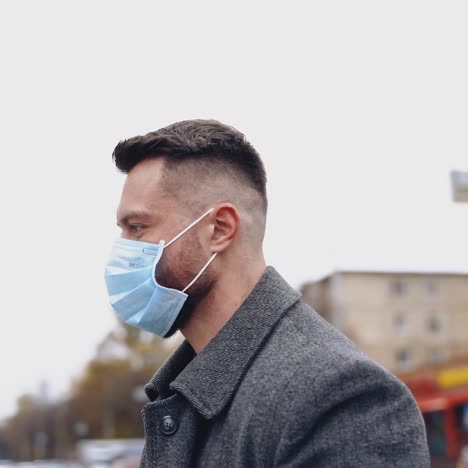 young businessman is posing outdoor with a strong expression and facial mask. male in gray coat and dark suit walking the street. concept video