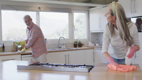 Middle-aged-caucasian-couple-cleaning-kitchen-at-home,-slow-motion