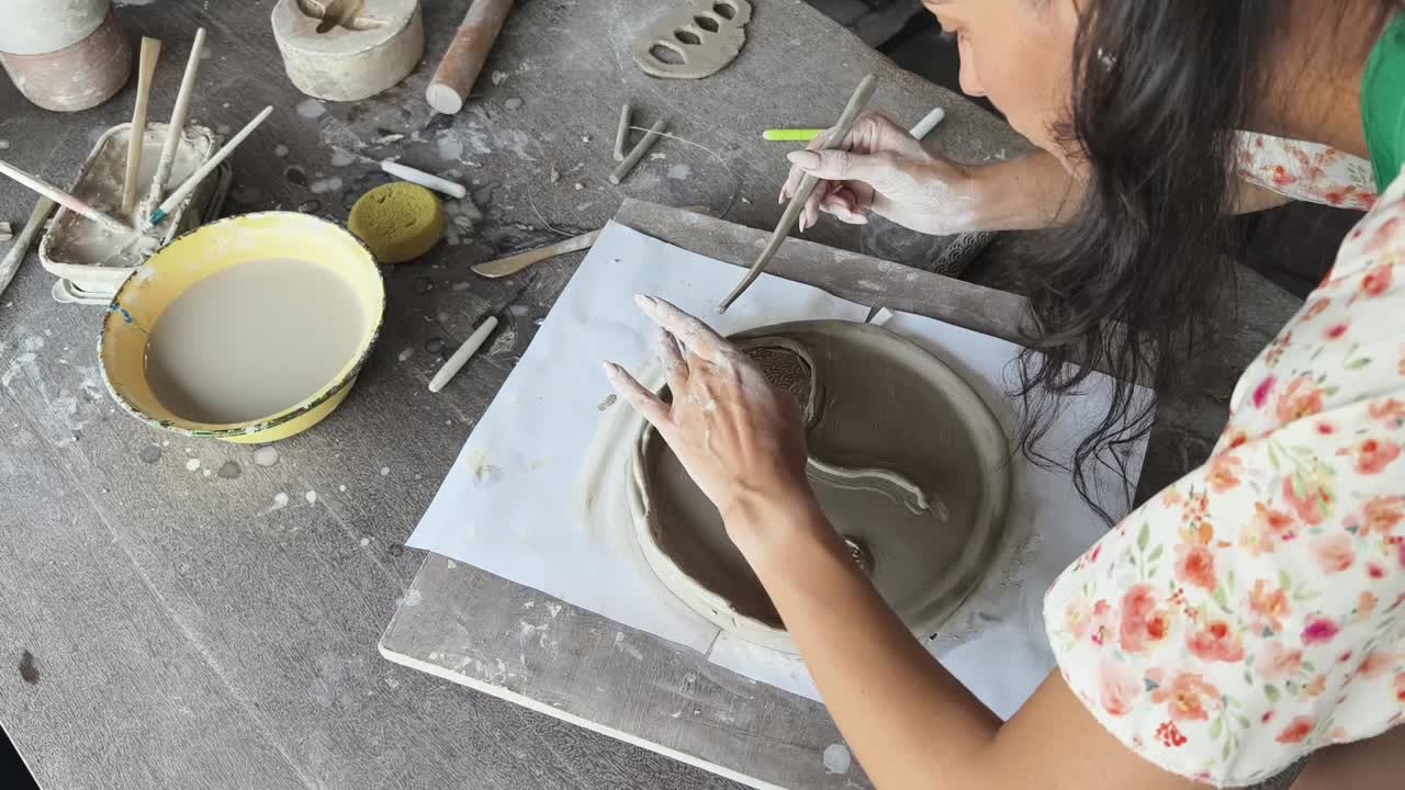 Donna che crea un piatto di ceramica con argilla in un laboratorio di ceramica