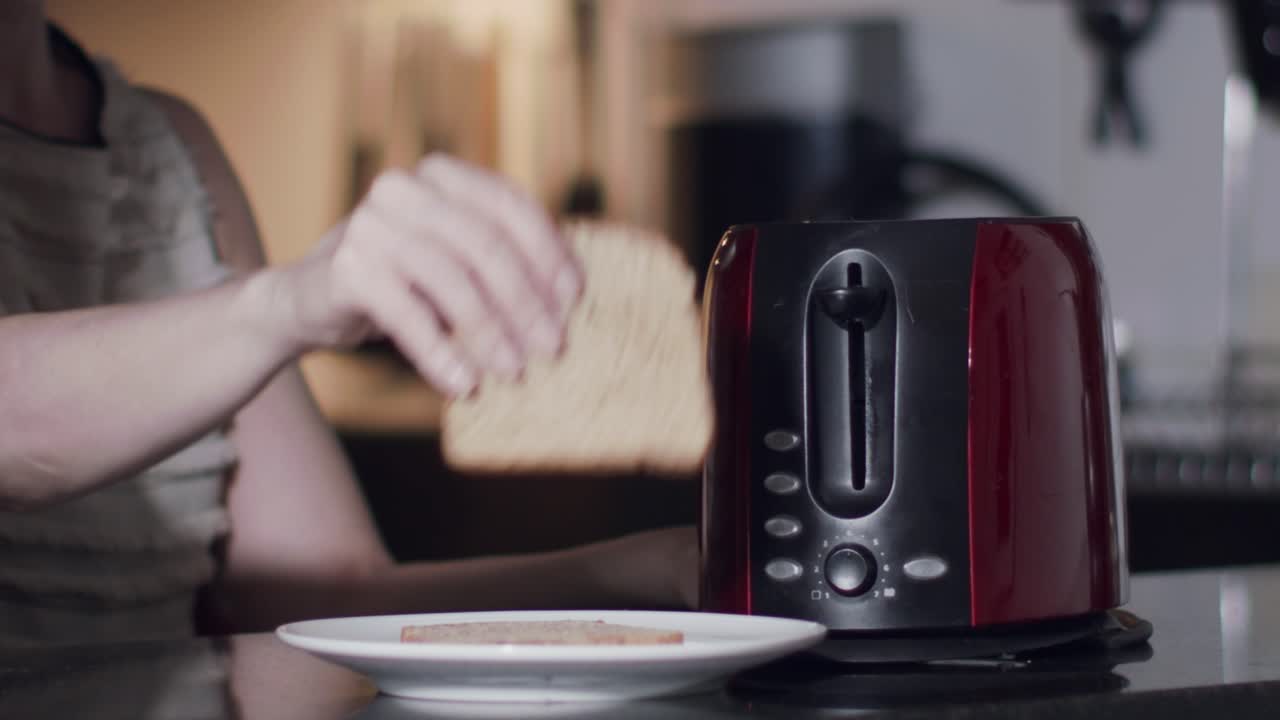 a caucasian female model puts slices of bread in a toaster - slow motion shot