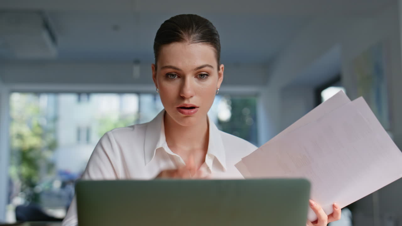 Confused worker reviewing documents sitting laptop closeup. Shocked woman