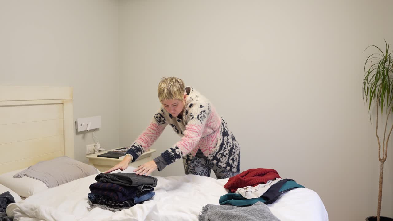 Woman folding clothes on bed