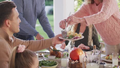 Video-Von-Glücklichen-Kaukasischen-Eltern,-Töchtern-Und-Großeltern,-Die-Essen-Am-Tisch-Im-Freien-Servieren