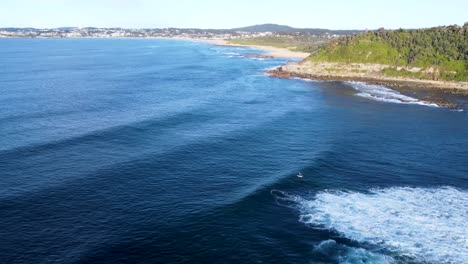 Drohnen-Luftlandschaftsaufnahme-Von-Landzunge-Und-Kajakfahrer-In-Morgenwellen-Am-Forresters-Beach-Central-Coast-Pacific-Ocean-NSW-Australien-4k