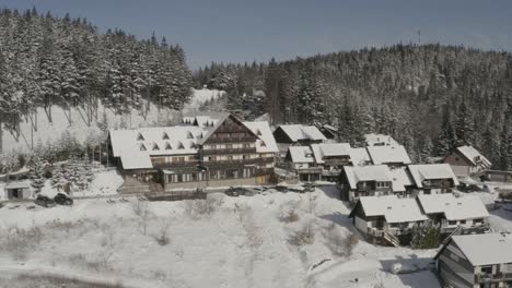 Lukov-Dom-winter-resort-with-cabins-in-the-Pohorje-mountains-Slovenia,-Aerial-dolly-out-reveal-shot