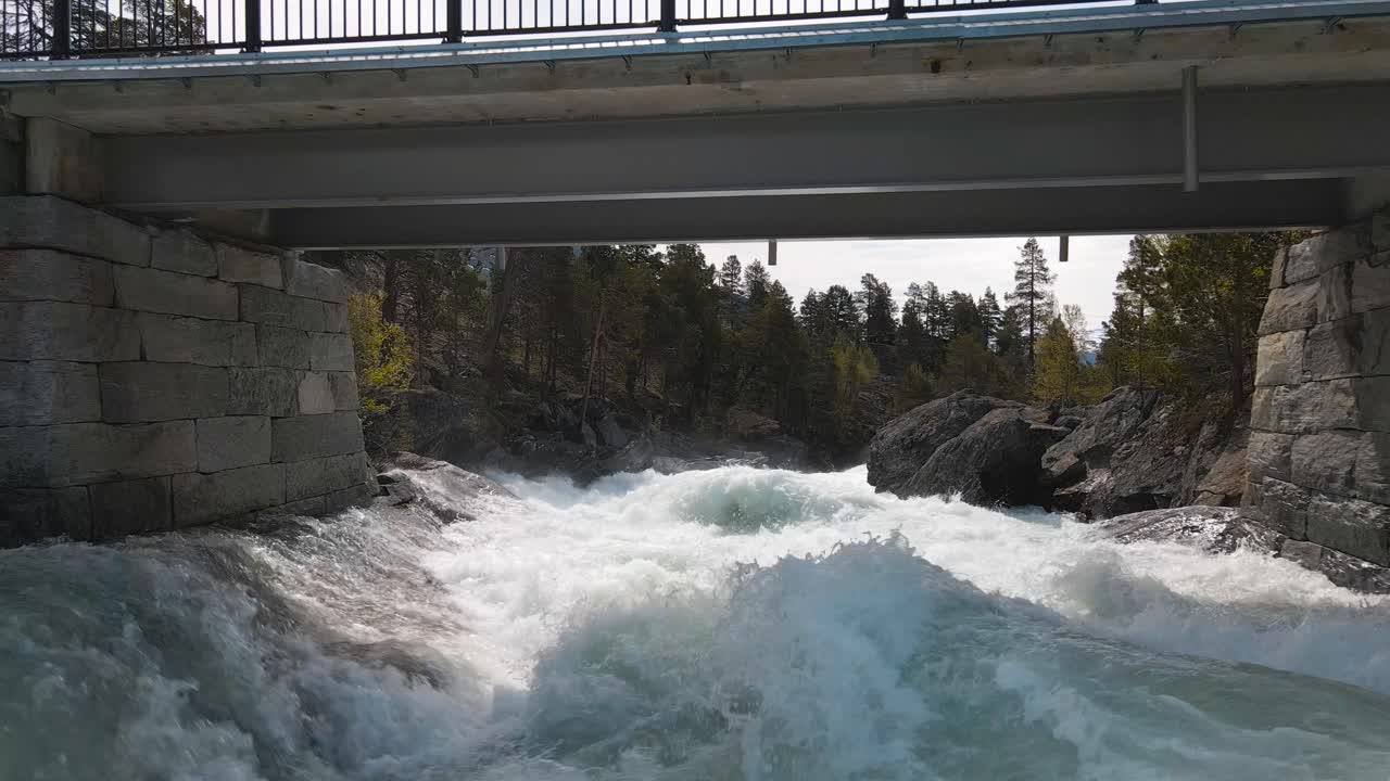 Srone footage following along fast flowing river, under bridge in Norway, Billingen