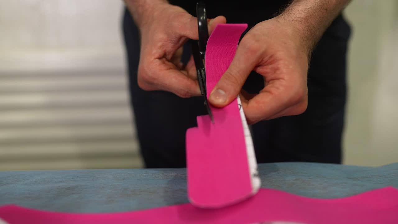 persona cortando tela rosa con unas tijeras