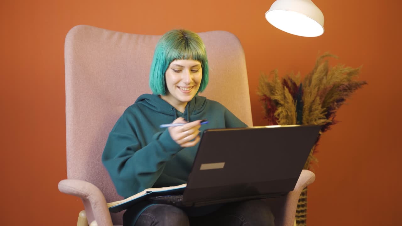 행복한 표정으로 노트북에서 일하는 젊은 여성.