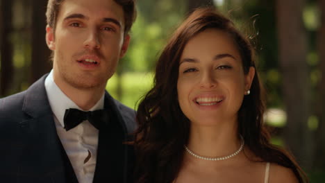 una joven pareja mirando a la cámara en el parque. la novia y el novio de pie en el jardín.