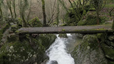 rustic wooden bridge over forest stream - aerial