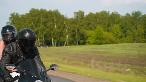 Motorcyclist-with-girlfriend-travels-by-cycle-at-countryside