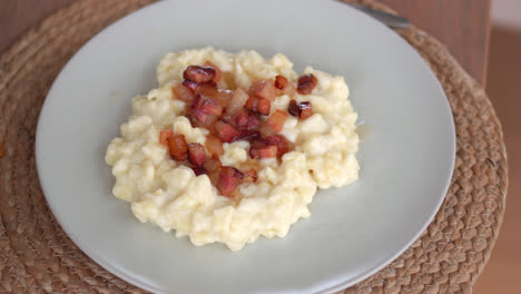 di gustosi gnocchi di bryndzove halusky in un piatto cosparso di pezzi cotti di grasso di maiale affumicato