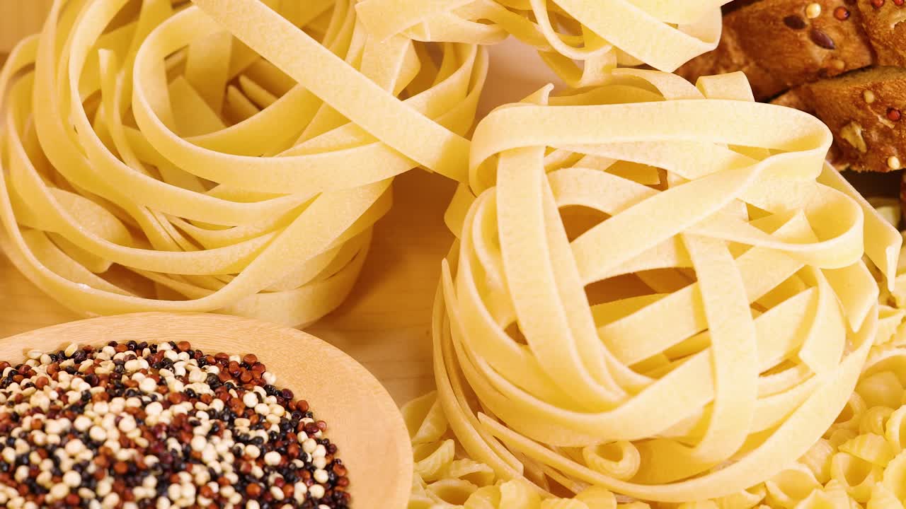 A close-up view of various pasta and grains, including quinoa and tagliatelle, arranged in a warm, inviting setting