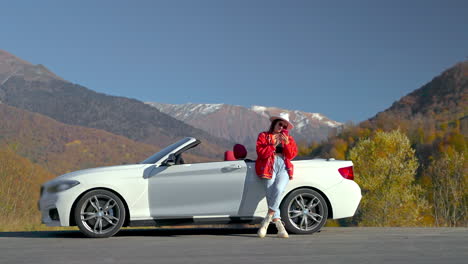 woman relaxing in convertible car by mountains