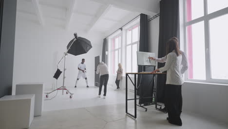 the designer art director producer are watching the photos on the computer monitor for a photo shoot discussing and choosing the best one for the magazine cover. discuss looking at the monitor