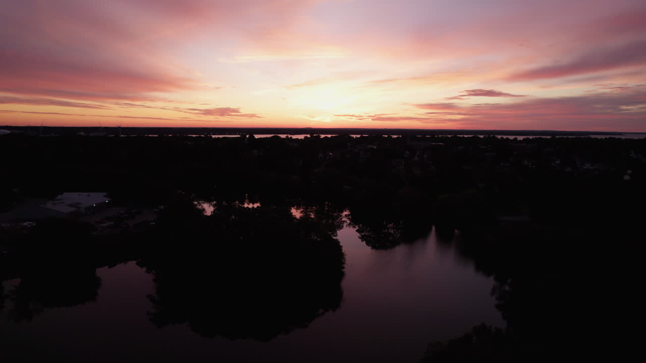 Beautiful tilting aerial view of an orange sunset over lakes and forests