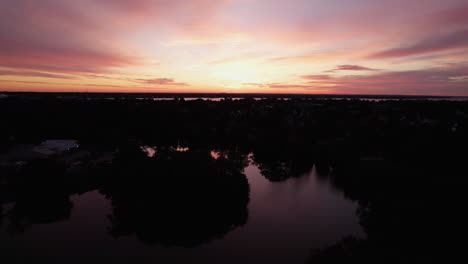 beautiful tilting aerial view of an orange sunset over lakes and forests