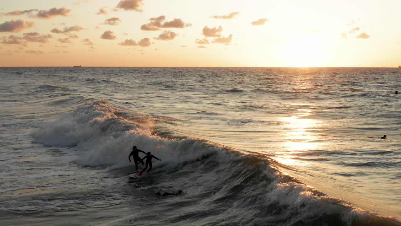 surfistas frente a la ciudad turística domburg en los países bajos durante la puesta de sol