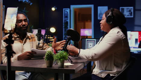 show host talking with guest, filming video for social media platforms using cellphone on tripod
