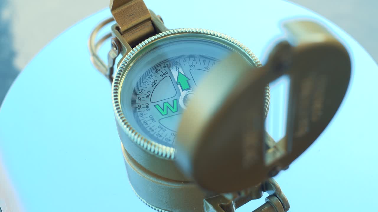 una brújula vintage retro dorada giratoria, 360 grados, iluminación, naturaleza, cámara lenta, primer plano, 4k