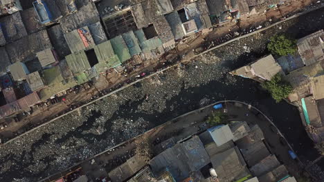 Vista-Aérea-De-Arriba-Hacia-Abajo-En-Canala-Sucia-Con-Basura-En-El-Barrio-Pobre-De-Dharavi,-Mumbai,-India