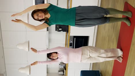 mujer madura positiva con hija discapacitada practicando yoga en casa, cámara lenta