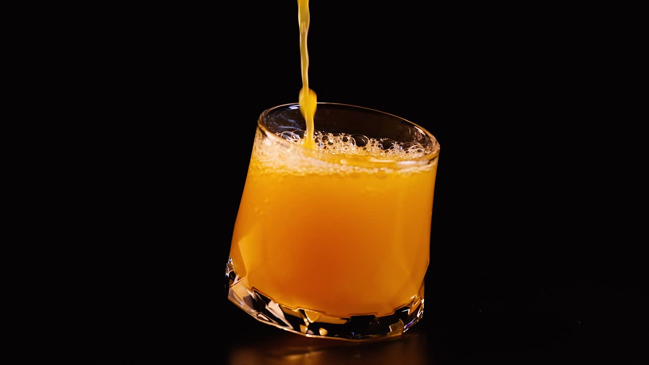Succo d'arancia versato su sfondo nero