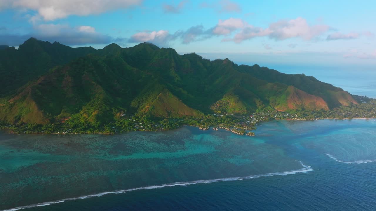 Golden hour sunset Cooks Opunohu Bay Moorea island French Polynesia aerial drone Mount Mauaroa Tohivea Rotui clouds boats lagoon bungalows coral reef waves Pacific Ocean forward pan up motion