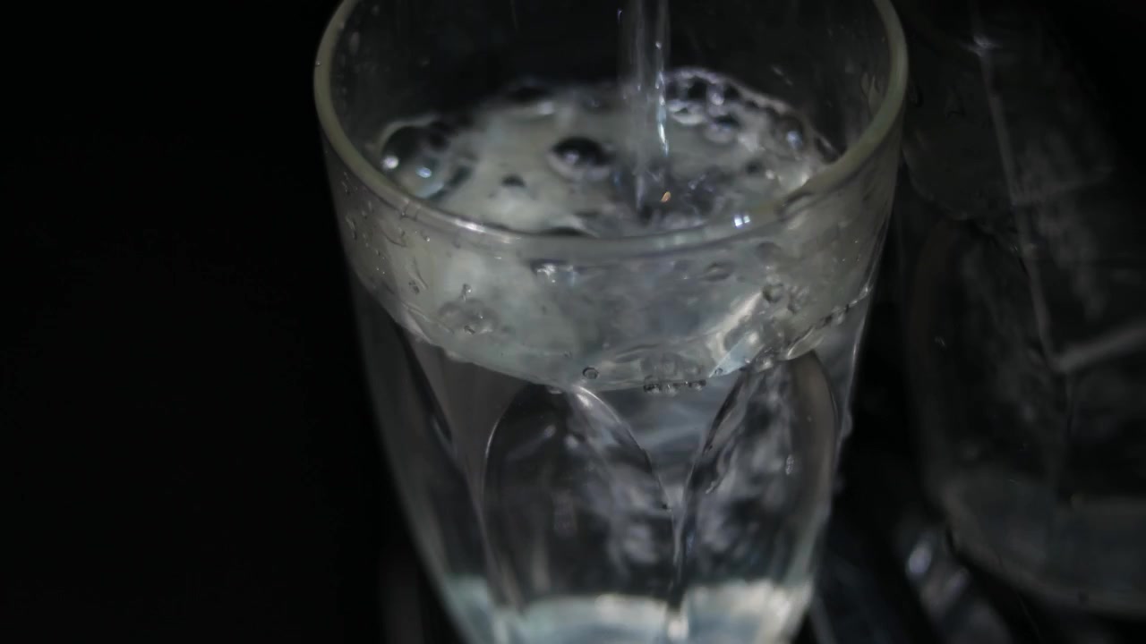 Primo piano di un bicchiere che versa acqua