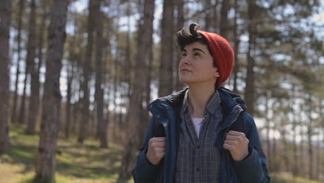 a young woman with short hair in a red woolen hat looks around in the forest