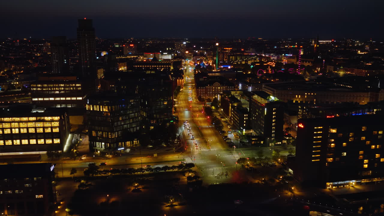 Aerial drone view of Islands Brygge and Copenhagen's inner harbor with colourful reflections on the water and the Tivoli Gardens at night in Denmark